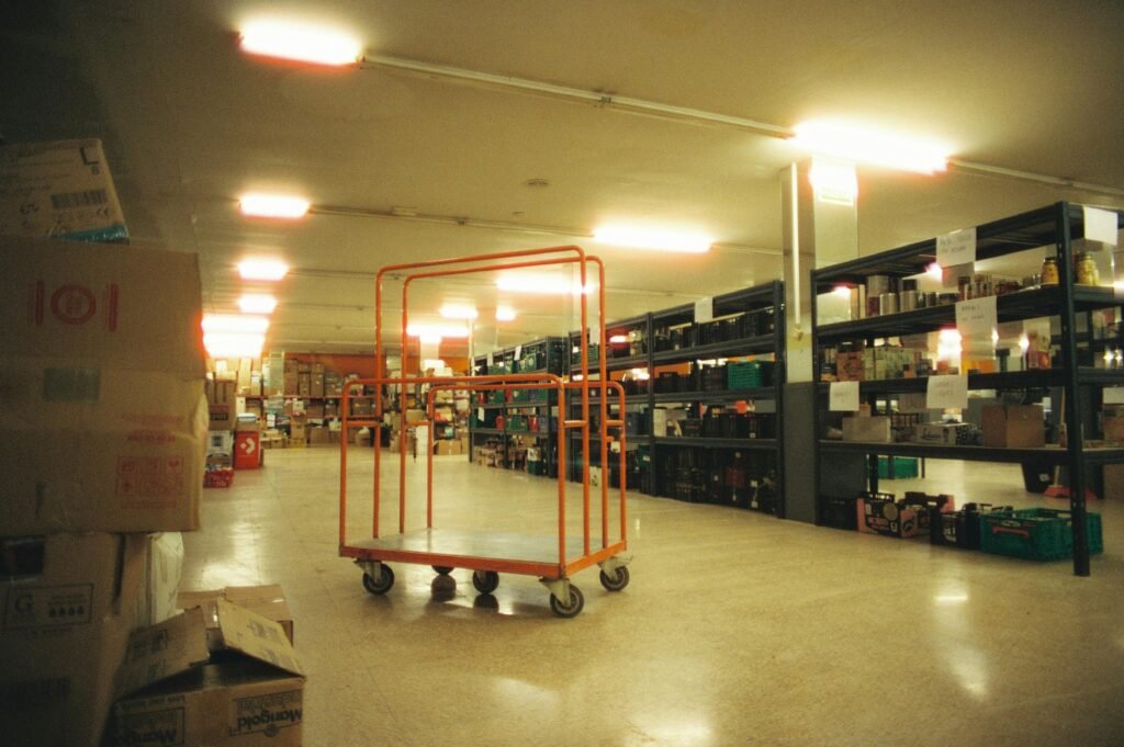 Industrial warehouse interior featuring shelves and an orange cart, ideal for logistics.