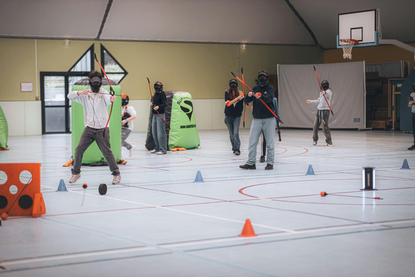 Jeunes jouant à l'arc dans une salle de sport.