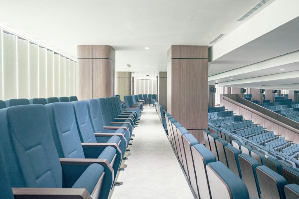 A modern theater interior with rows of plush blue seats and wooden accents, creating an elegant ambiance.