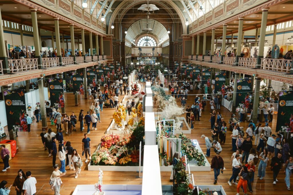 A bustling flower festival in Melbourne's Royal Exhibition Building showcasing vibrant floral displays and large crowds.