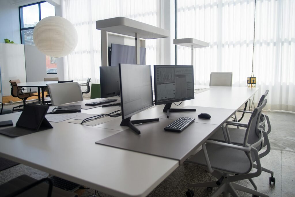 Bureau moderne et spacieux comprenant plusieurs ordinateurs, des chaises et des espaces de travail collaboratifs baignés de lumière naturelle. 